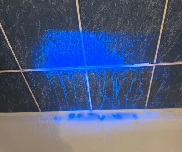 Colorant fluorescent UV révélant l'origine d'une fuite sur carrelage de salle de bain
