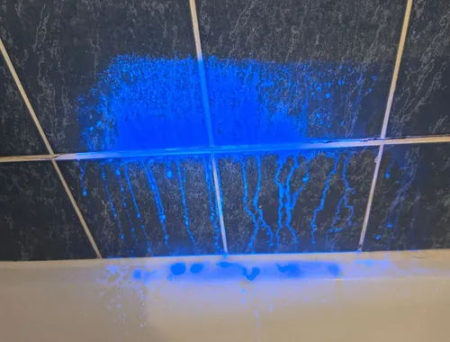 Colorant fluorescent UV révélant une fuite sur carrelage de salle de bain