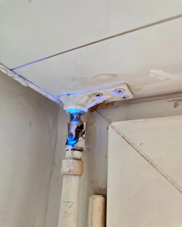 Fuite localisée à la lumière UV bleue sur un raccord de tuyauterie au plafond, mise en évidence lors d'une intervention de GBL Détection.
