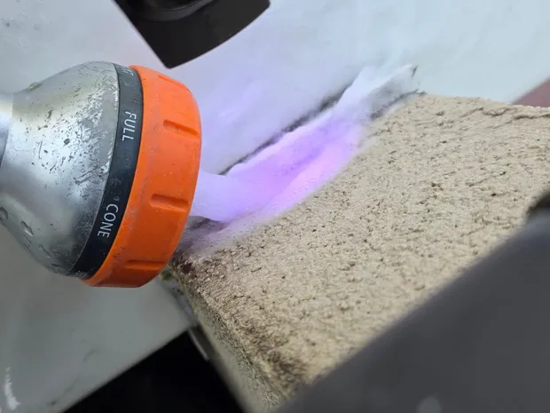 Technicien de GBL Détection utilisant une lampe UV pour révéler un colorant fluorescent violet sur un acrotère de toiture-terrasse.