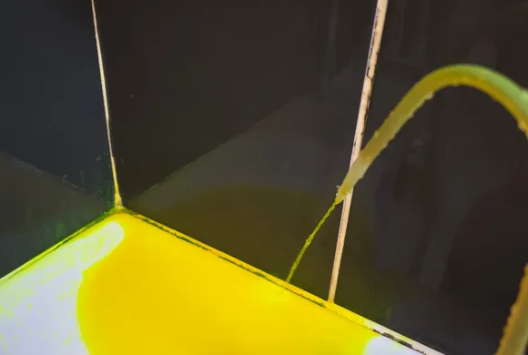 Application d'un colorant traceur jaune-vert fluorescent dans l'angle d'une douche pour localiser une fuite sur les joints, intervention de GBL Détection.