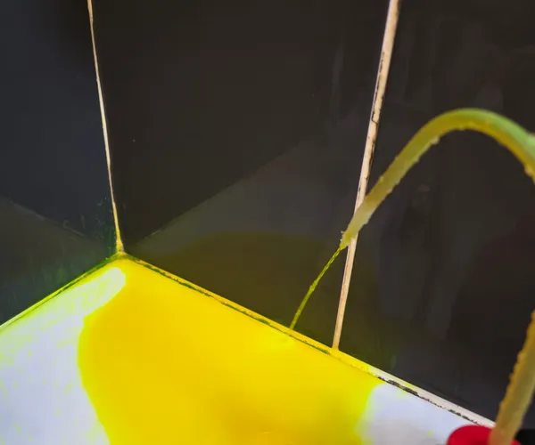 Colorant fluorescent jaune-vert révélant une fuite dans l'angle d'une douche