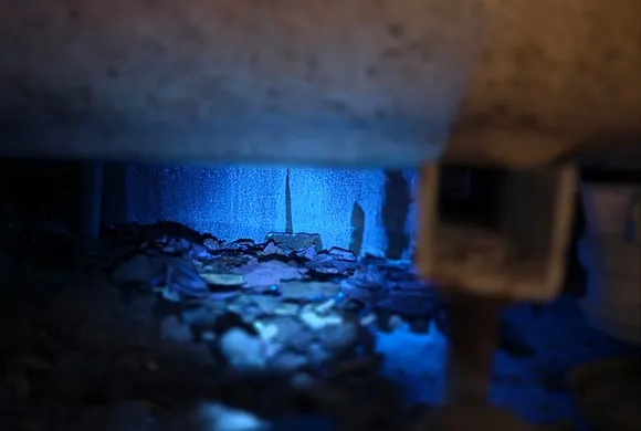 Aiguille de traçage plantée dans un vide sanitaire éclairé en lumière UV bleue lors d'une recherche de fuite par GBL Détection.