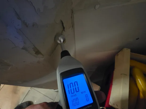 Humidimètre sans contact affichant 100 % de saturation sur un plafond décollé et taché d'humidité, diagnostic de fuite par GBL Détection.