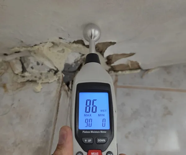 Humidimètre Pinless Moisture Meter affichant 86 % WET sur plafond endommagé par une fuite